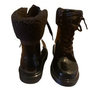 See By Chloe ankle-high PVC boots in black. Dark brown shearling.